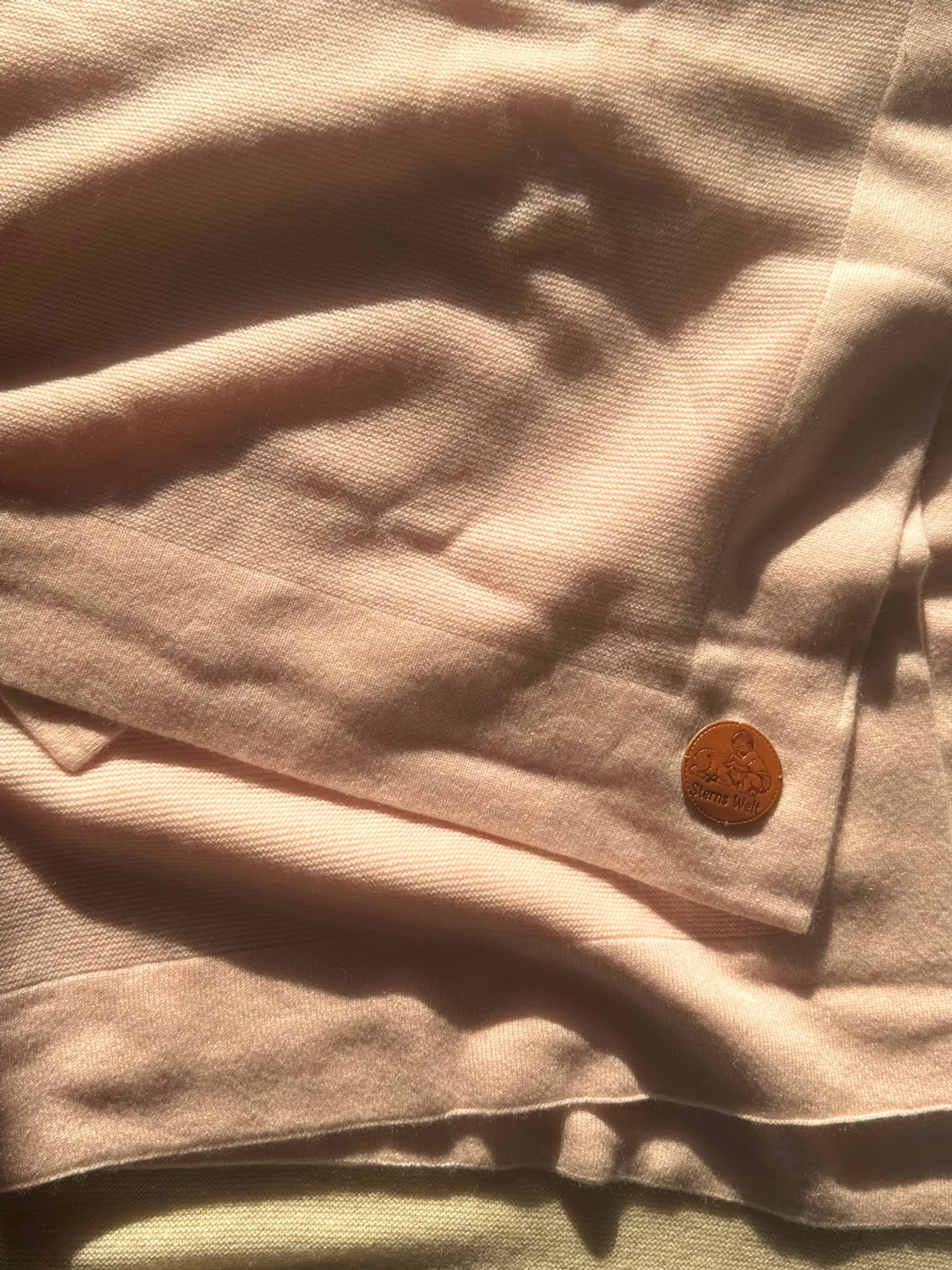 Detail der roséfarbenen Kaschmir Decke mit Sterns Welt Lederlabel